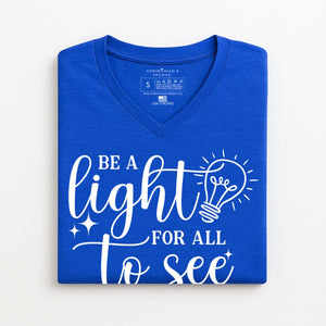 Folded Christian t-shirt that reads be a light for all to see