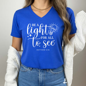 Person wearing a blue Christian t-shirt with Matthew 5:15 quote and light bulb graphic