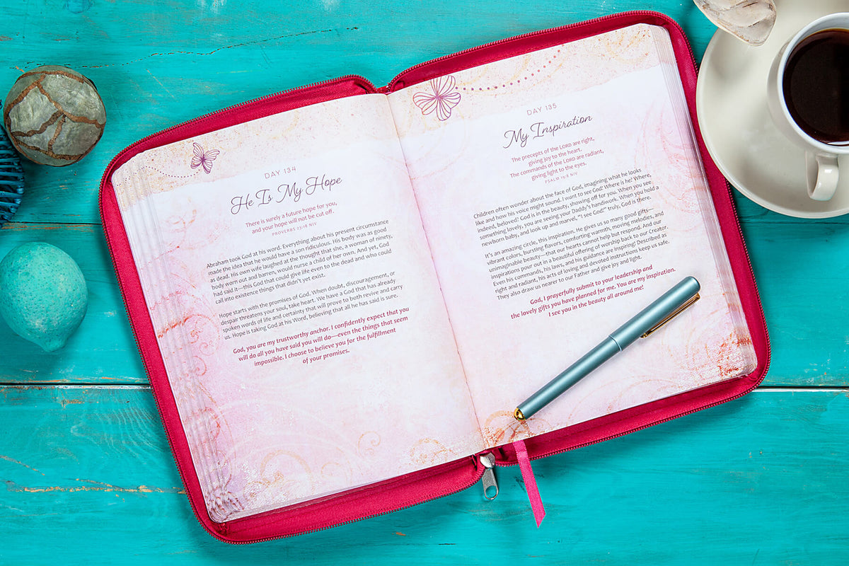 Open notebook with a pen on a teal wooden surface with a cup of coffee and decorative stones.