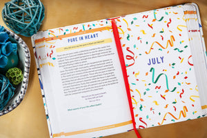 Open Bible devotional with colorful design on a wooden surface