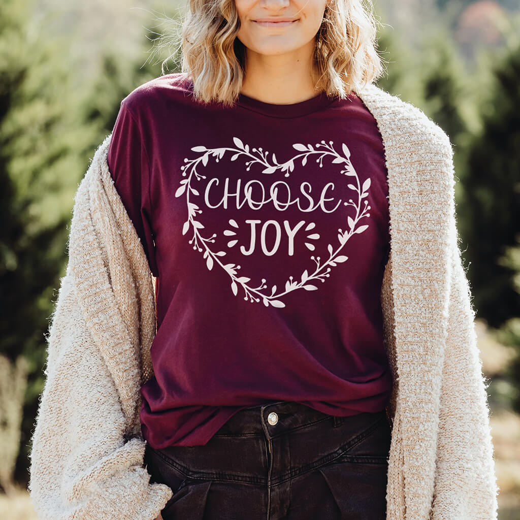 Woman wearing the maroon Choose Joy t-shirt with an off-white cardigan