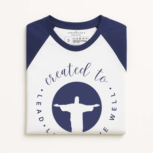 Created to lead live serve well graphic on a blue and white baseball tee