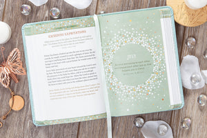 Open book with a green cover on a wooden surface with decorative items.