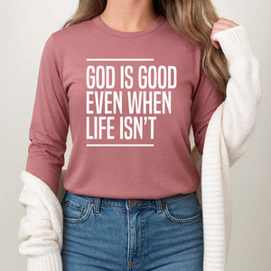 Young woman wearing a pink long-sleeve shirt with 'God is good even when life isn't' print