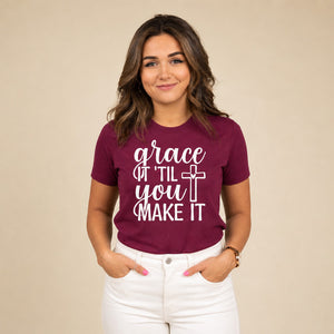 Woman wearing a maroon 'grace it til you make it' shirt with white pants