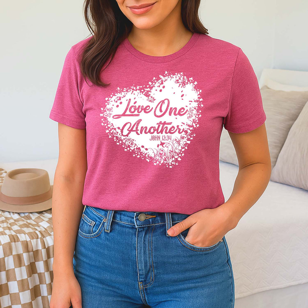 Woman wearing a pink screenprinted love one another John 13:34 t-shirt