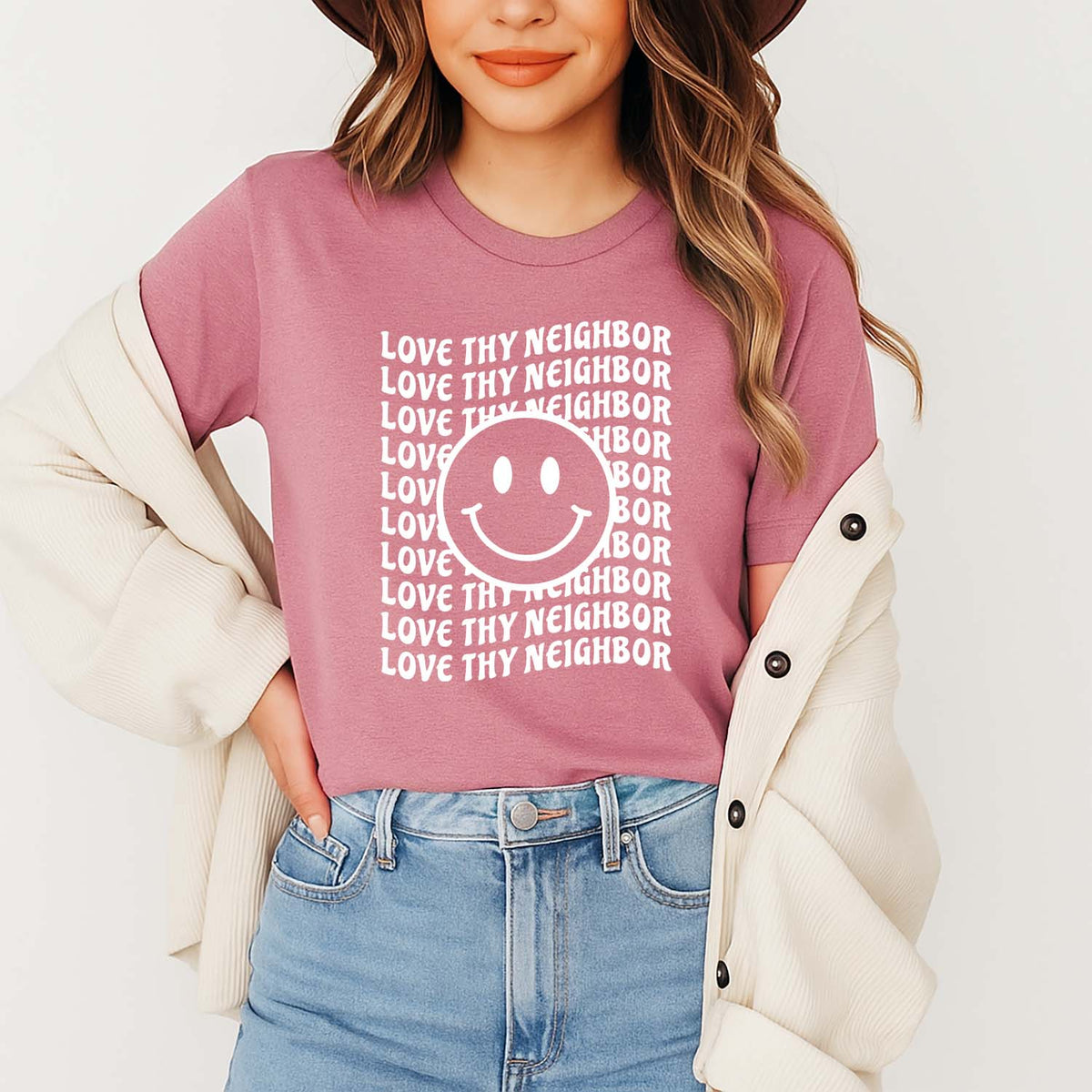 Smiling model wearing a love thy neighbor Christian top in mauve