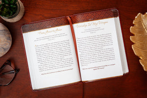 Open devotional with a decorative cover on a wooden surface