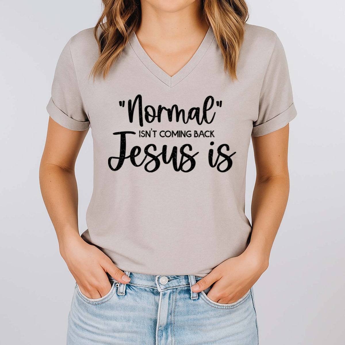 Person wearing a gray t-shirt with text 'Normal isn't coming back Jesus is' on a plain background