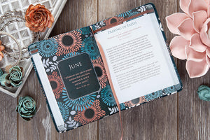 Floral-patterned planner with June page on a wooden surface with flowers.