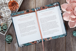 Open book with floral design on a wooden surface with flowers around