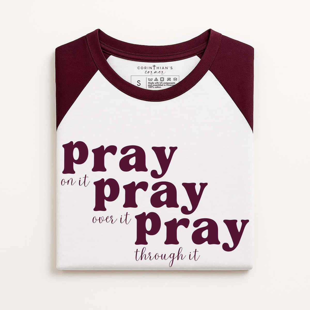 White and burgundy baseball shirt with faith-based text on a white background