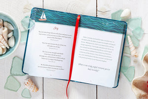 Open book with a red ribbon on a wooden surface with seashells