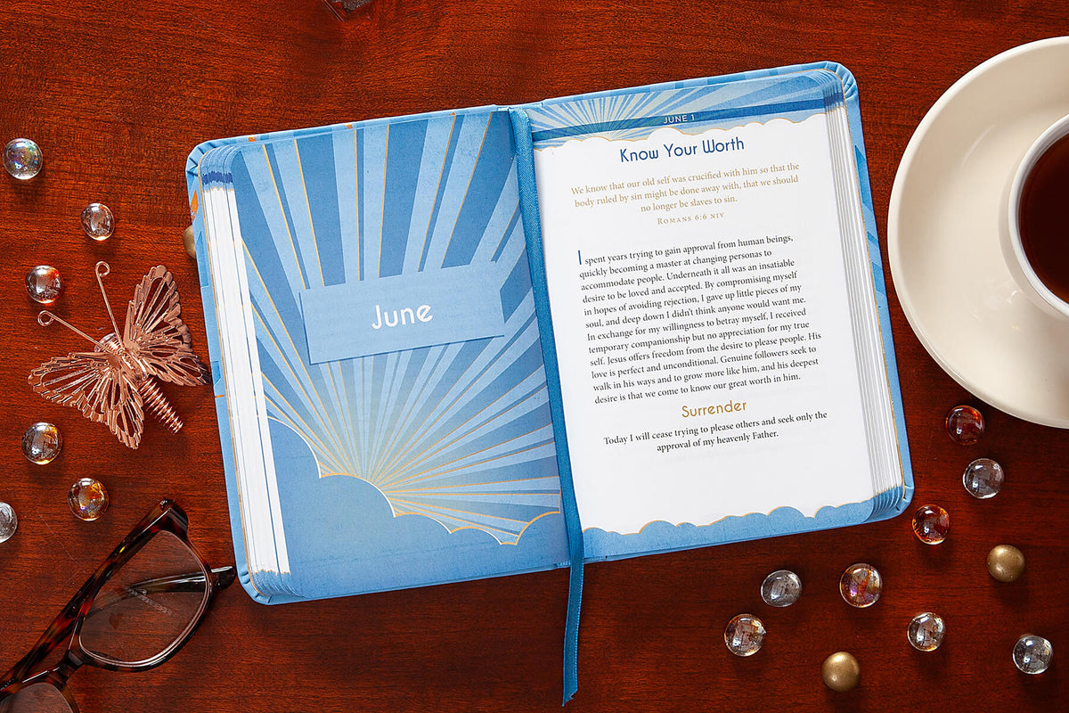 Open devotional with a page titled 'Know Your Worth' on a wooden surface with a cup of tea and glasses.