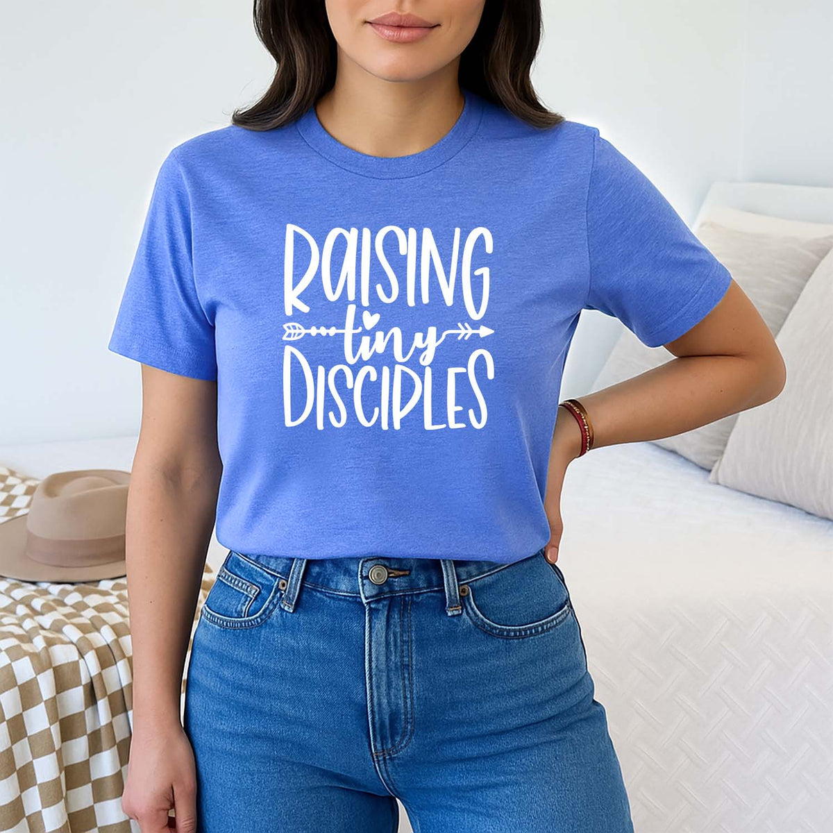 Young mom wearing a blue t-shirt with 'RAISING tiny DISCIPLES' text in a casual setting.