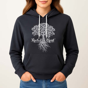 Dark hoodie with a tree design and 'Rooted in Christ' text on a young woman