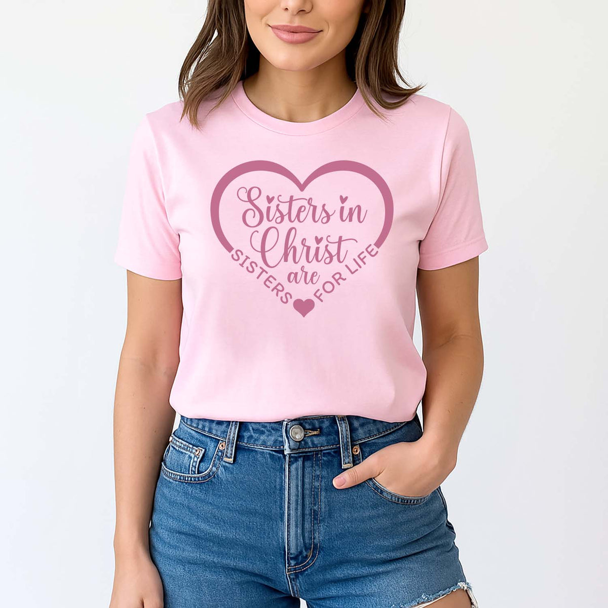 Young woman wearing a pink t-shirt with 'Sisters in Christ are sisters for life' text on a white background