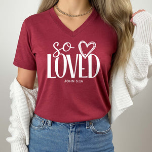 Red t-shirt with 'So Loved' text worn by a person, against a neutral background