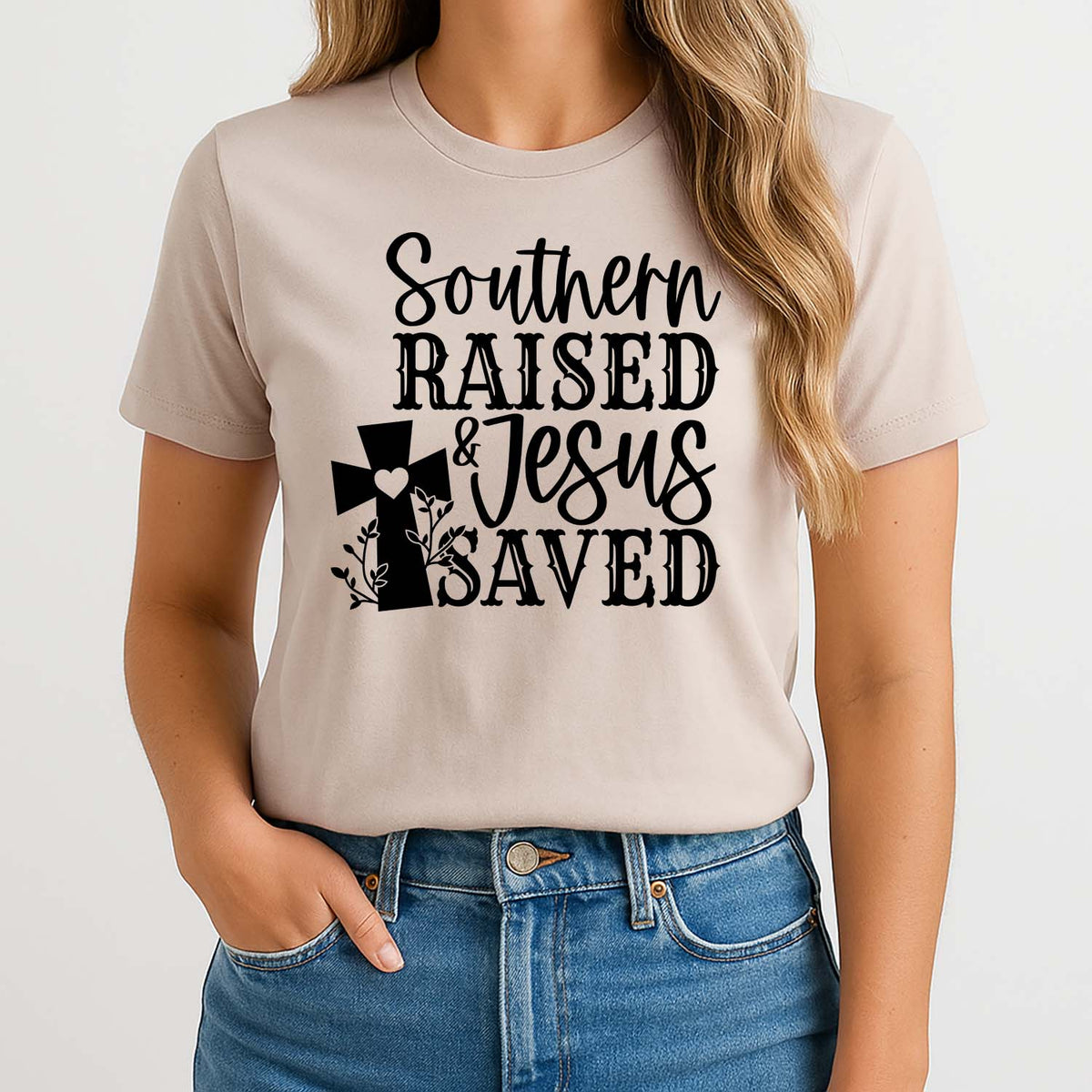 Woman wearing a beige t-shirt with 'Southern Raised & Jesus Saved' text and cross design.