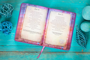 Open devotional with decorative cover on a teal wooden surface