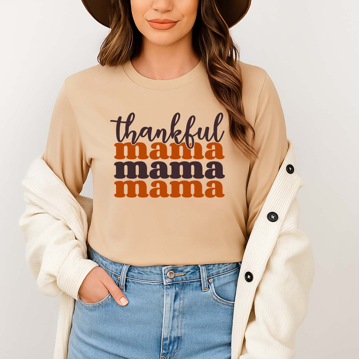 Woman wearing a beige Christian long sleeve with 'thankful mama' while standing against a plain background