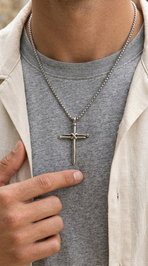 Person wearing a gray shirt with a cross pendant necklace