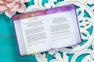 Open book with purple cover on a decorative teal surface with floral elements