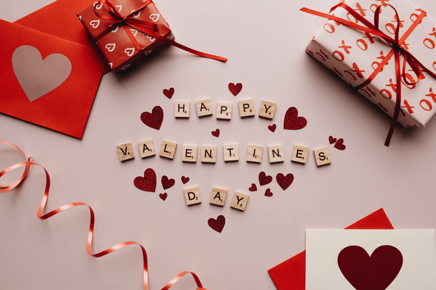 Happy Valentine’s Day written in Scrabble pieces with hearts and presents.