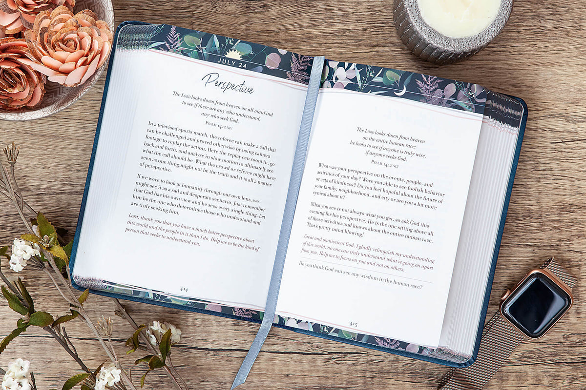 Open book on a wooden surface with floral decorations and a candle