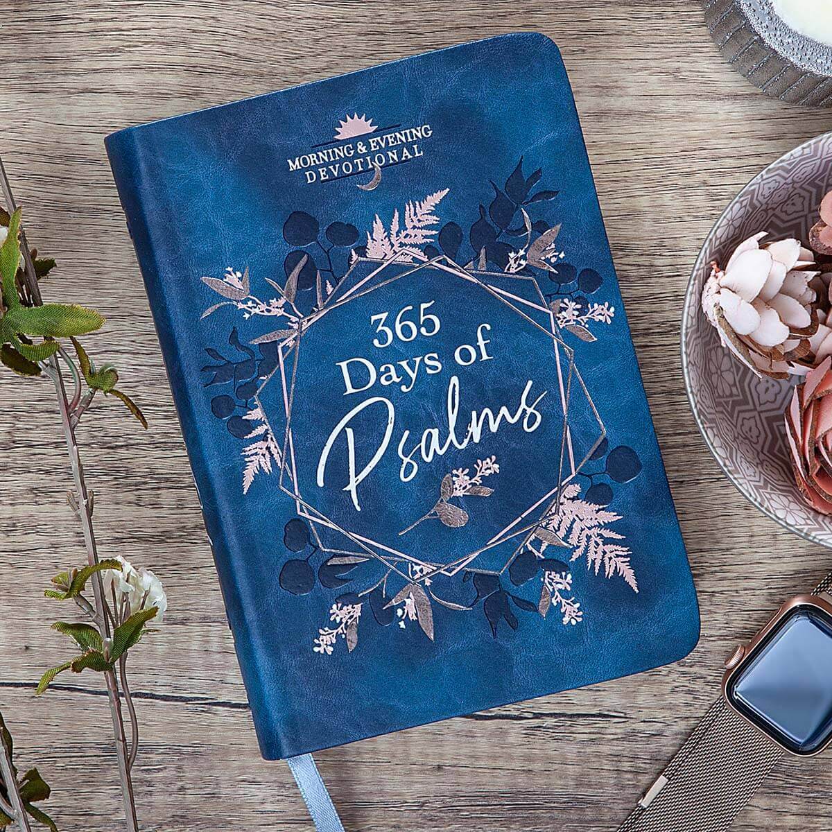 Blue devotional book titled '365 Days of Psalms' on a wooden surface with a plant and bowl in the background.