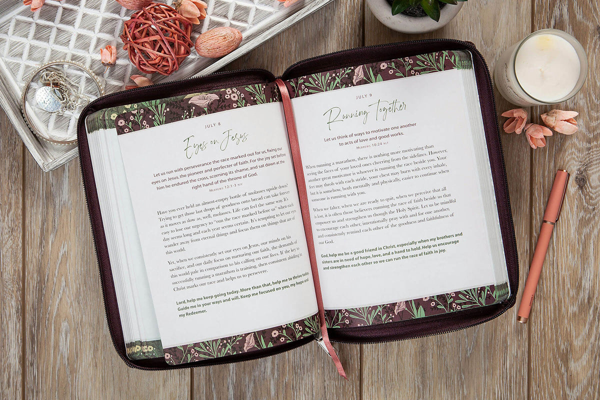 Open planner with floral design on a wooden surface with candles and decor.