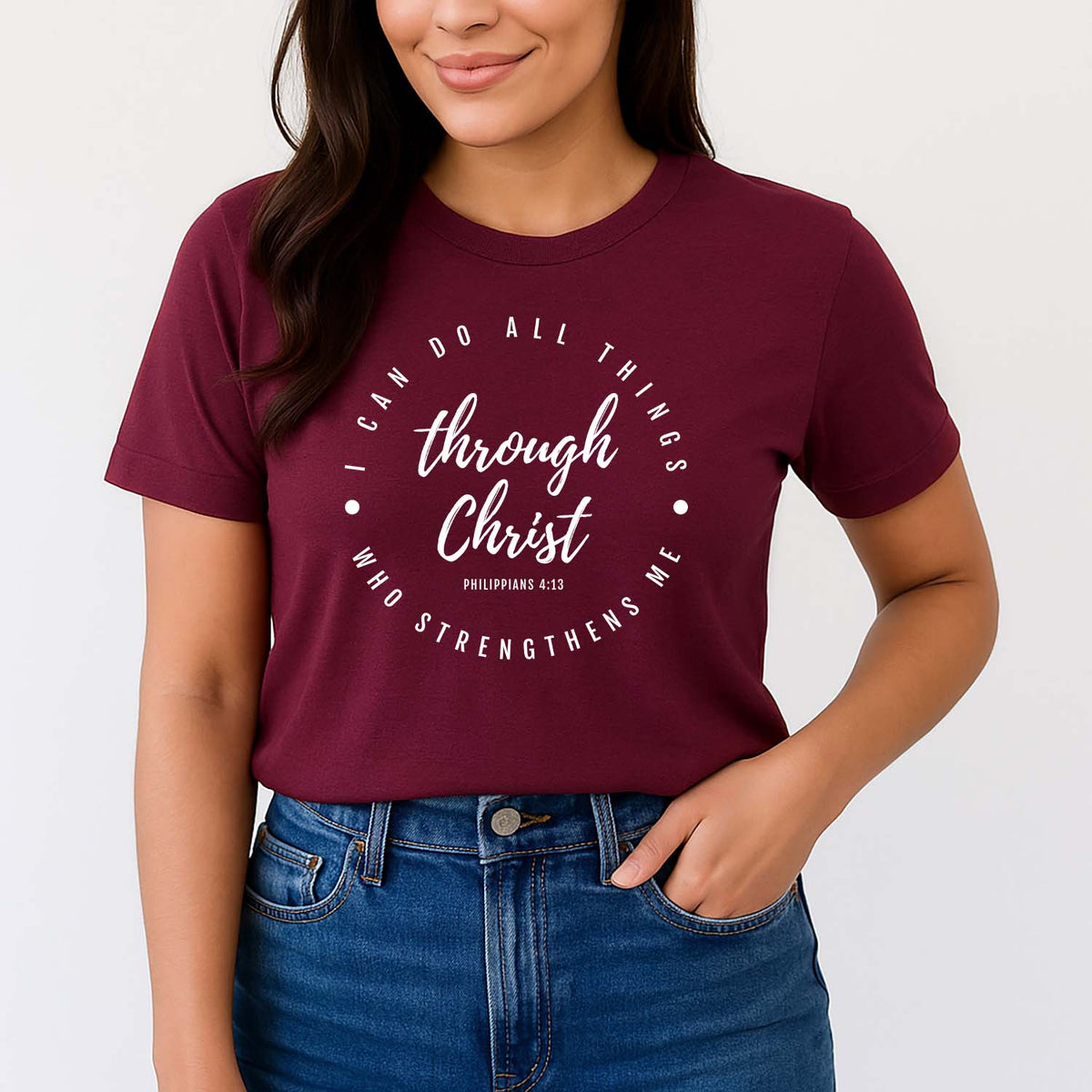 Woman wearing a maroon t-shirt with Philippians 4:13 on a plain background