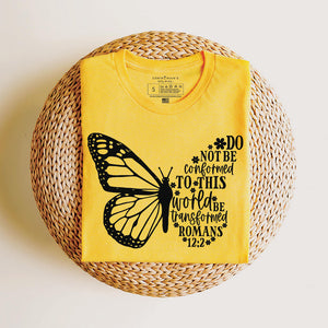 Folded yellow t-shirt that reads do not be conformed to this world be transformed Romans 12:2
