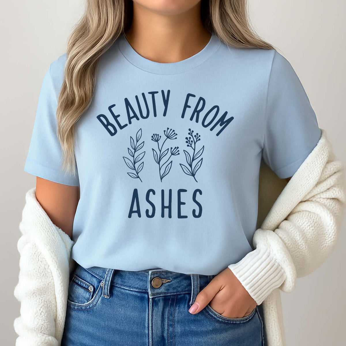 Woman wearing a light blue Beauty from Ashes t-shirt with a white cardigan