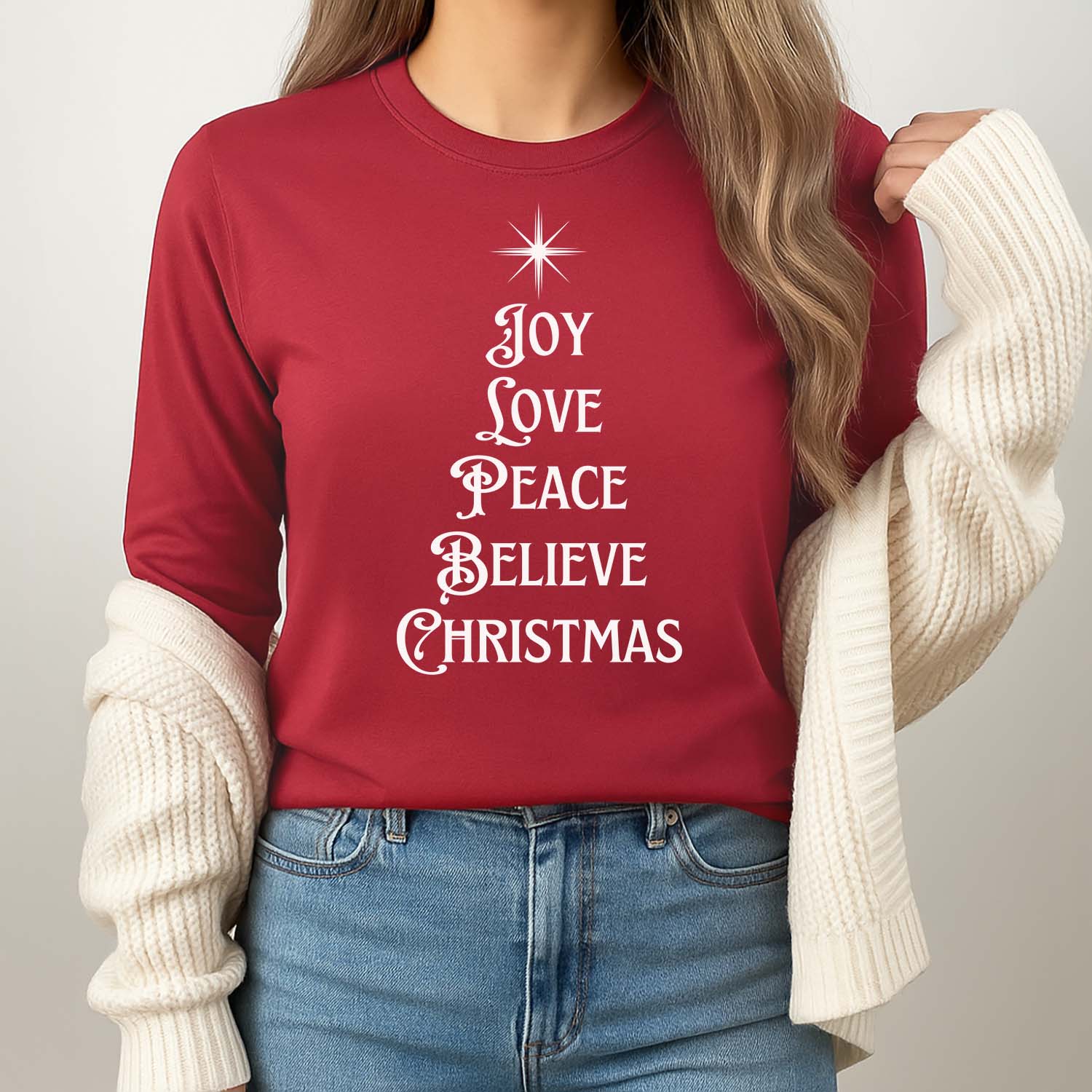A festive 'Joy Love Peace Believe Christmas' design in white on a cardinal long sleeve