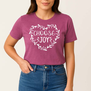 Person wearing a pink t-shirt with 'CHOOSE JOY' text on a plain background