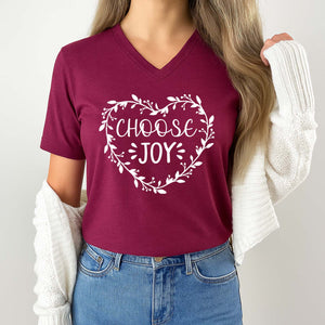 Person wearing a maroon t-shirt with 'CHOOSE JOY' text and floral design on a plain background