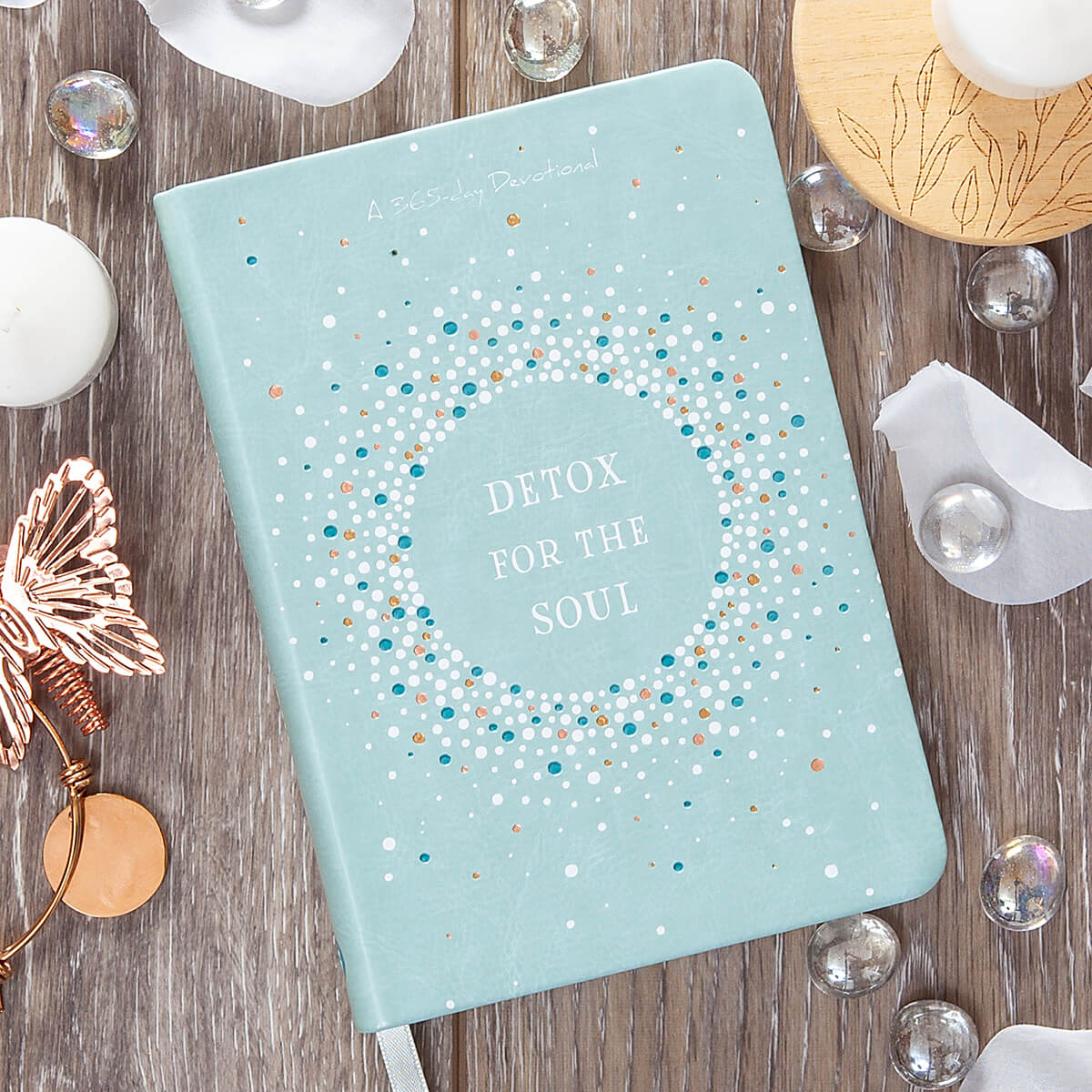 Light blue notebook with 'Detox for the Soul' text on a wooden surface with decorative items.