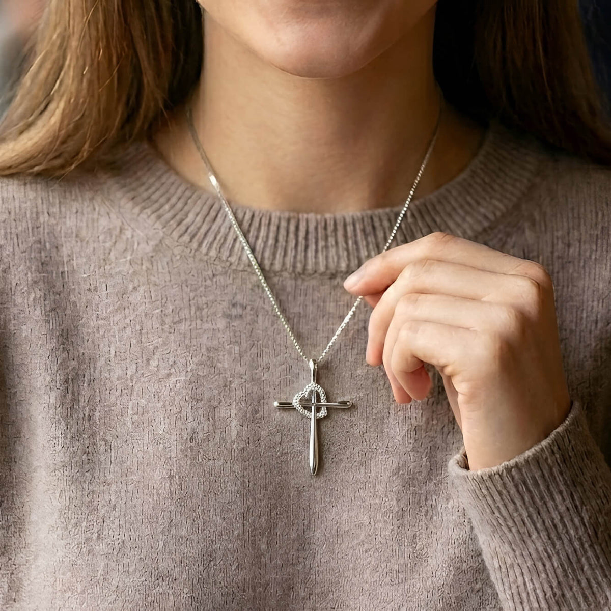 Person wearing a silver necklace with a cross pendant