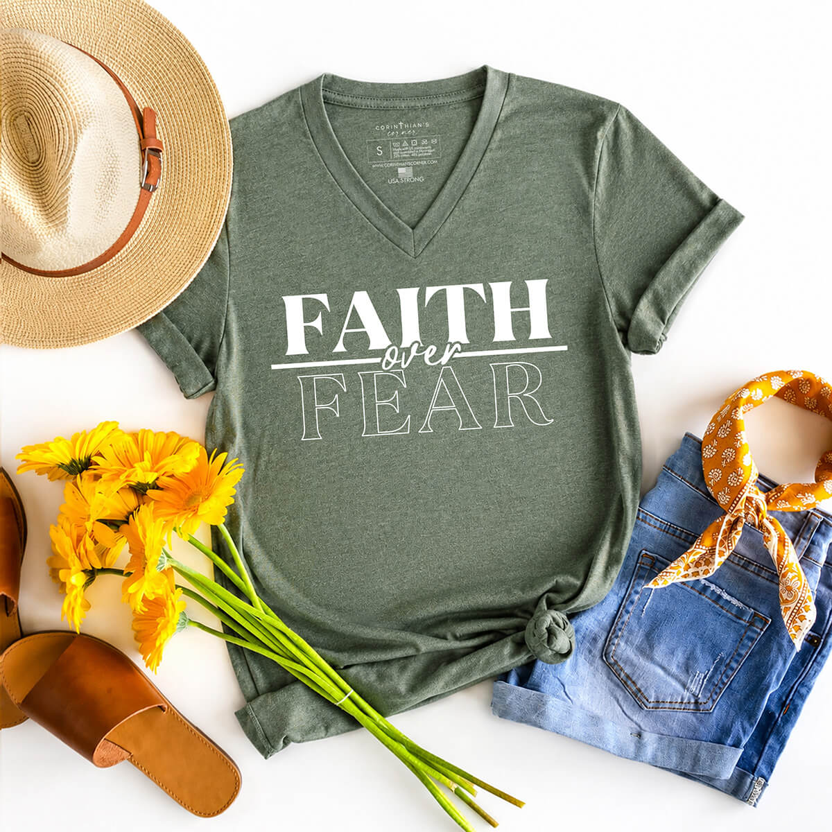 Green t-shirt with 'Faith over Fear' text, straw hat, yellow flowers, sandals, denim shorts, and bandana on a white background.