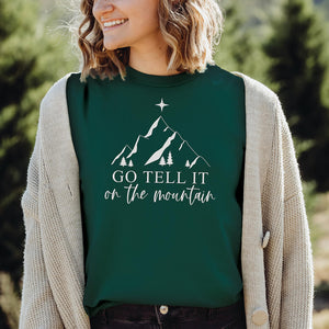 Woman in the woods wearing a go tell it on the mountain Christmas t-shirt