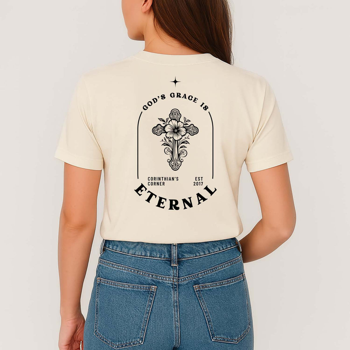 Person wearing a cream Christian t-shirt with a Biblical graphic design and text on the back, standing against a plain background.