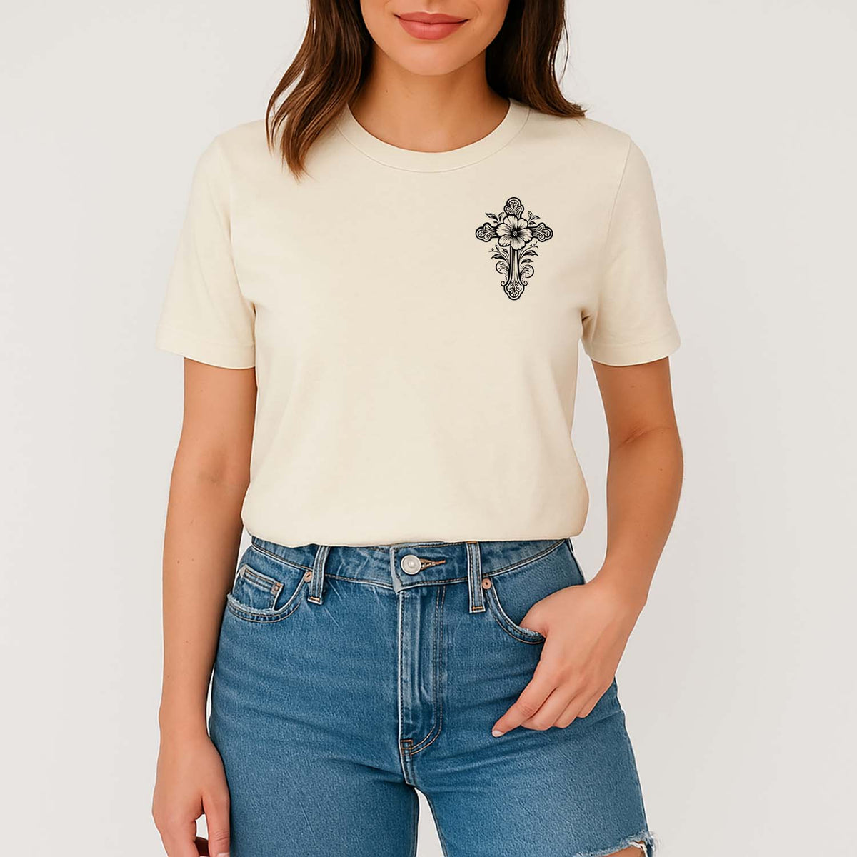 Person wearing a cream t-shirt with a black floral design and blue jeans on a white background