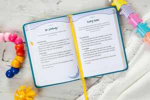 Open book with text on a white surface with colorful children's toys around