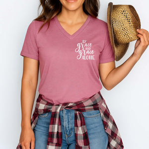 Person wearing a pink t-shirt with 'By grace and grace alone' text, holding a straw hat against a white background