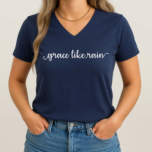 Woman wearing a navy blue t-shirt with 'grace like rain' text on a plain background