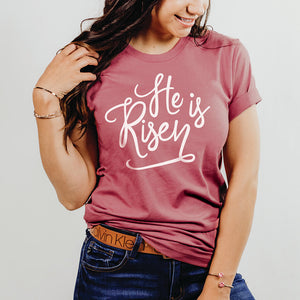 Smiling young woman wearing the mauve he is risen t-shirt to celebrate Easter