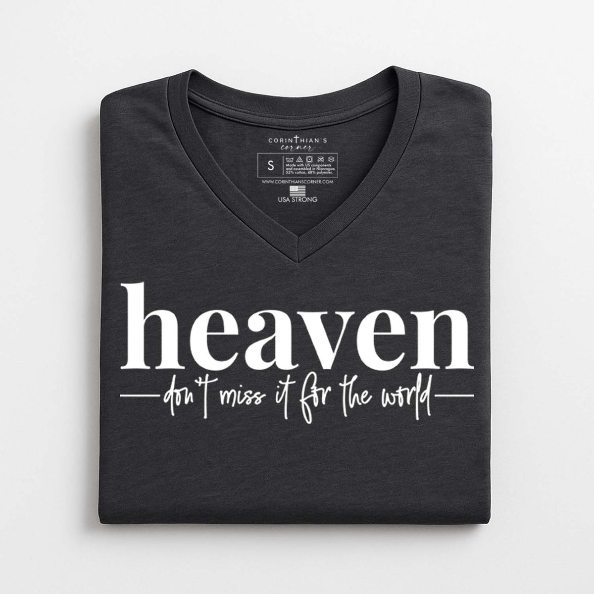 Folded black t-shirt with 'heaven don't miss it for the world' text on a white background