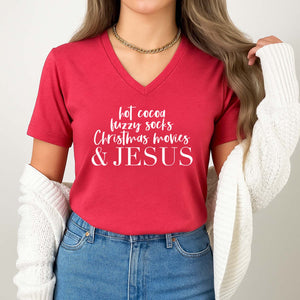 Person wearing a red t-shirt with text 'hot cocoa, fuzzy socks, Christmas movies & JESUS' on a plain background
