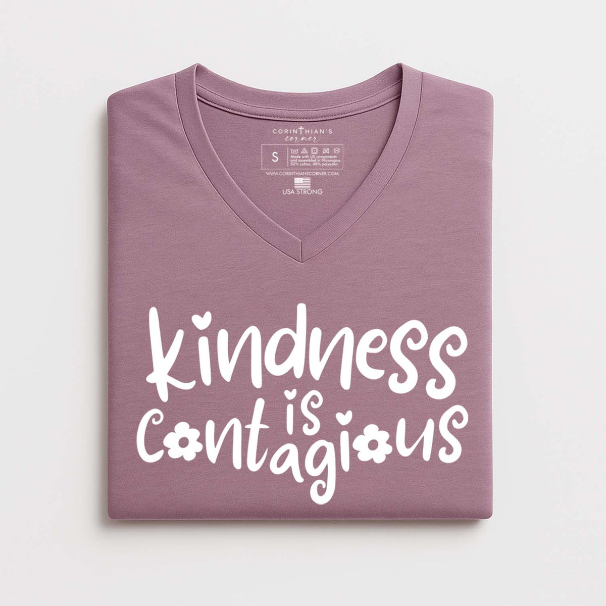 Folded purple t-shirt with 'kindness is contagious' text on a white background